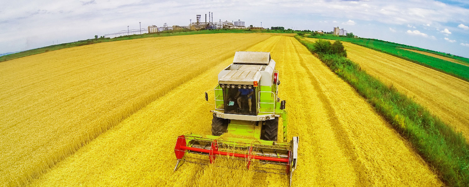 Tractor with chemicals plant in the background