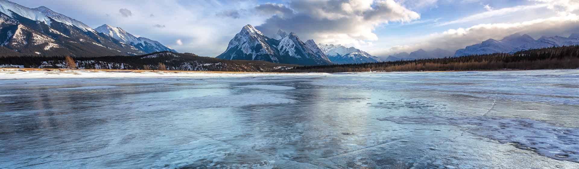 Bubbles beneath a frozen lake surface with snow capped mountains.