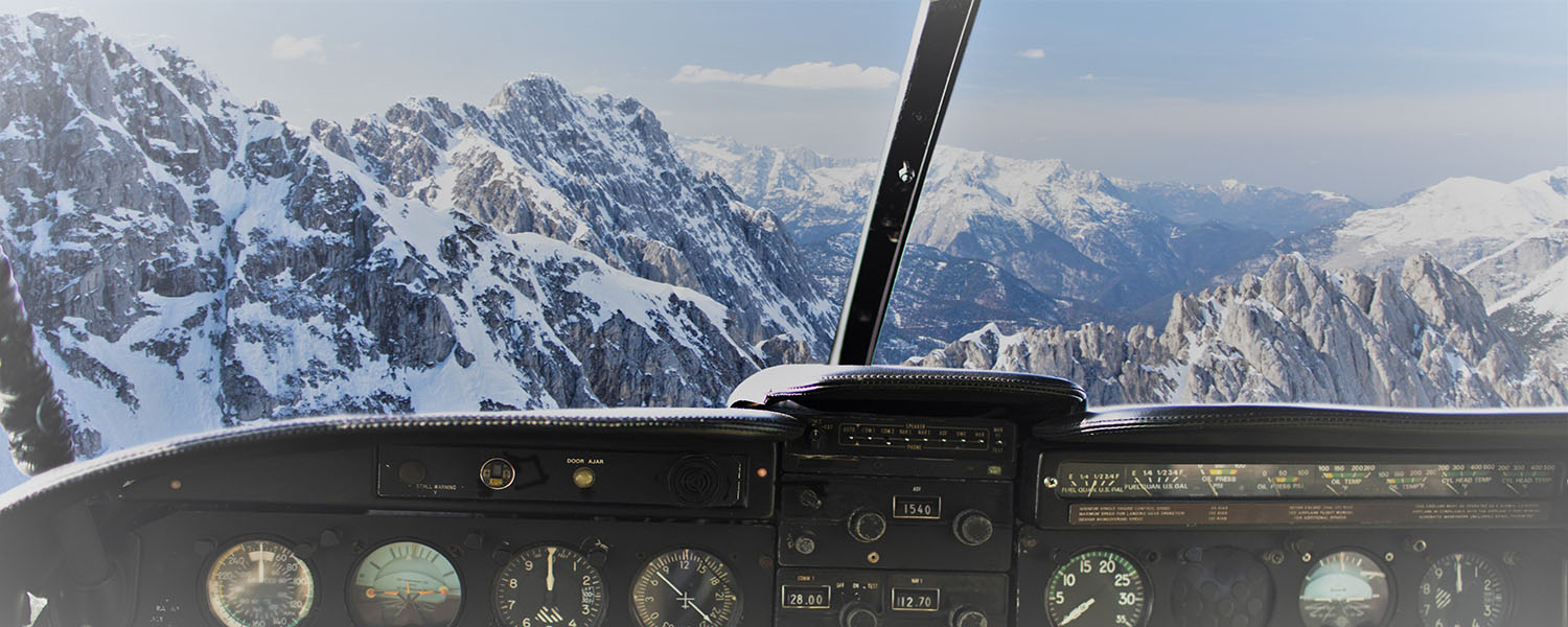 Looking out of a plane from the cockpit facing snow covered mountains