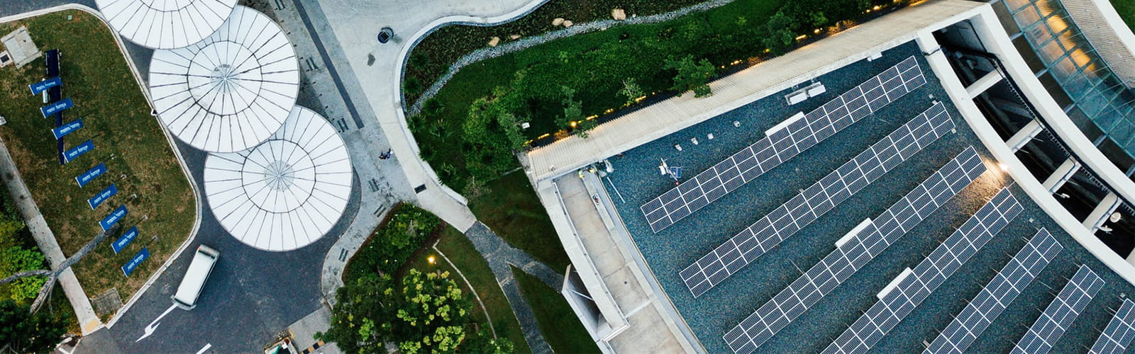 Aerial view of solar panels on top of a building and round white discs on a road.