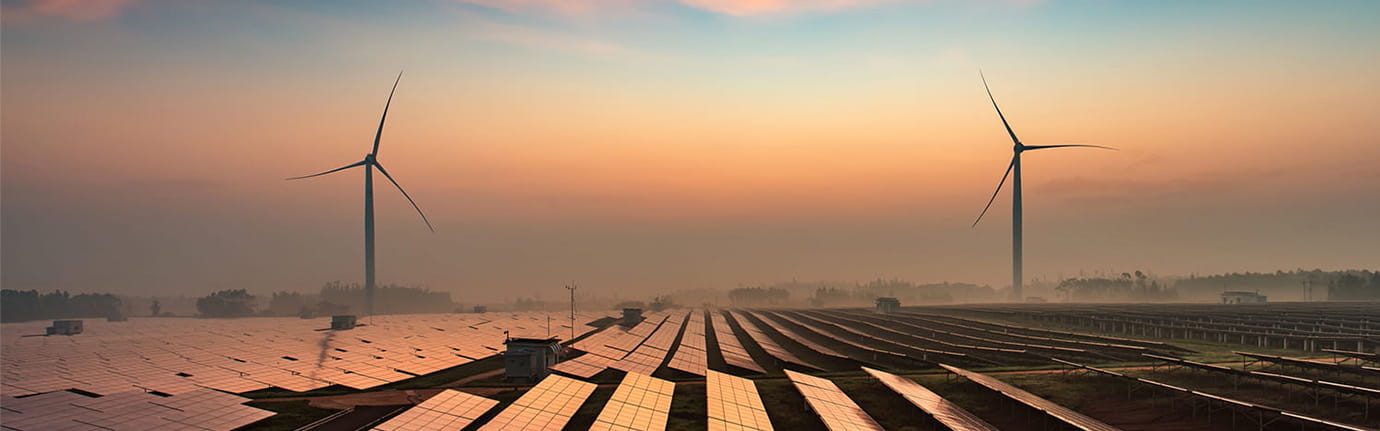 Solar panels and wind turbines creating energy at twilight.