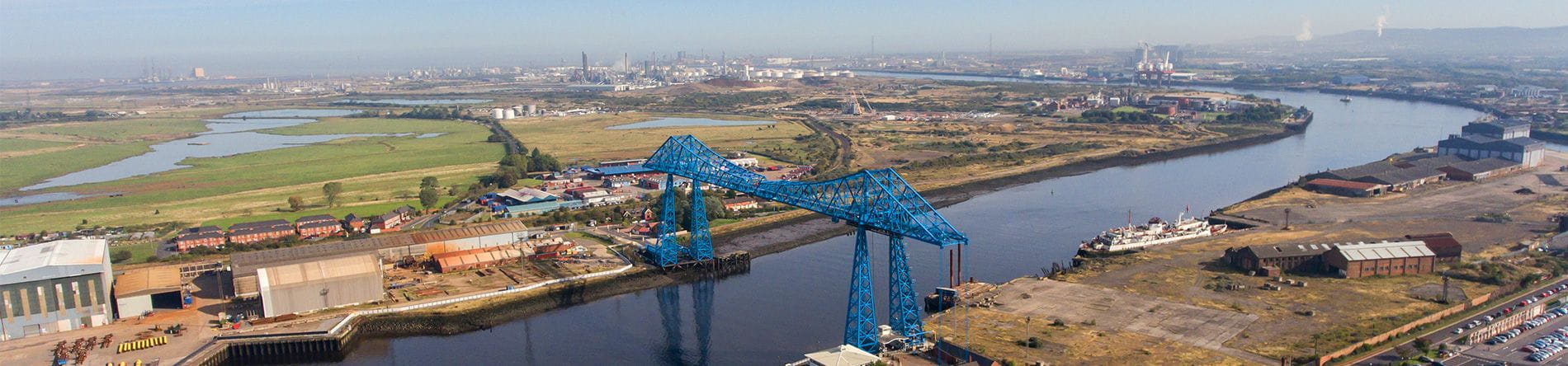 Aerial view of a blue transporter bridge over the Tees River in Middlesborough.